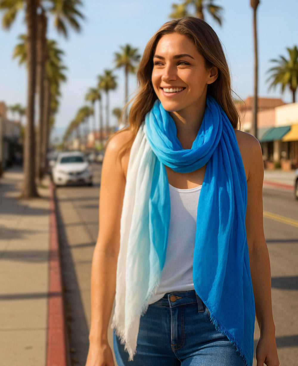 Woman wearing a blue and white scarf in a sunny outdoor setting with palm trees.