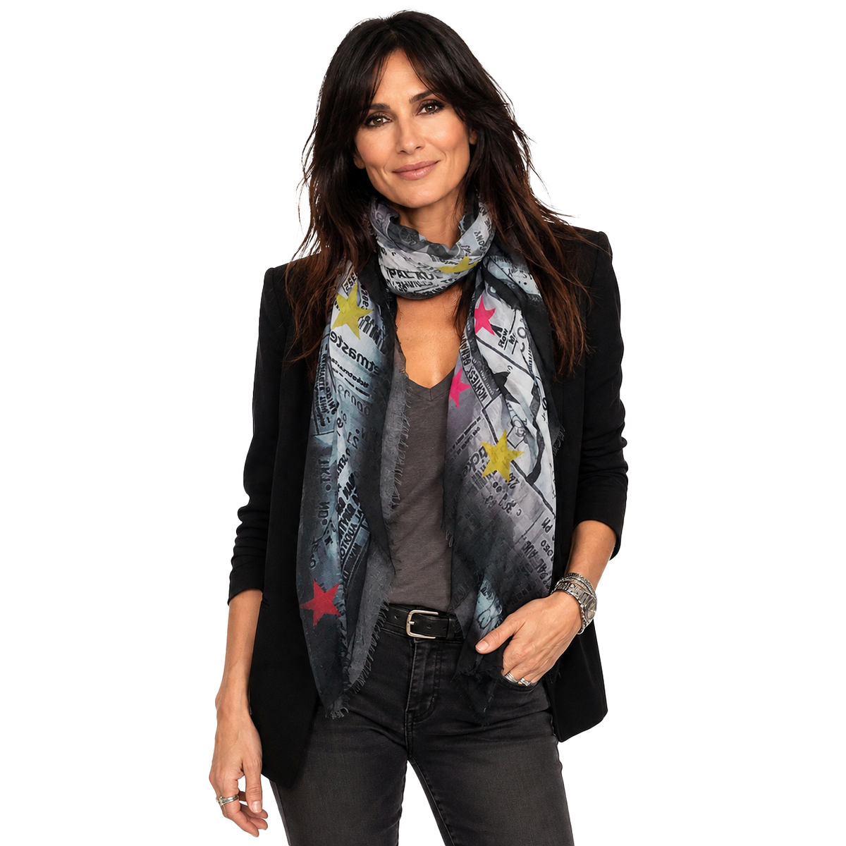 A woman modeling a black blazer, gray top, and dark gray jeans, wearing a patterned scarf with newspaper print and colorful star accents.
