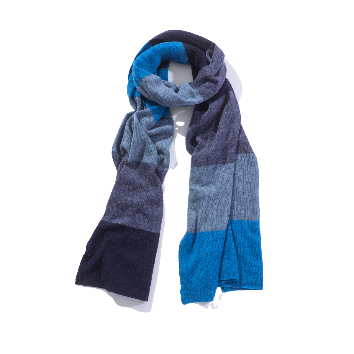 A knit scarf with a color-blocked pattern in shades of blue, navy, and gray, draped on a white mannequin torso against a white background.
